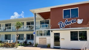 Un edificio de dos pisos con un letrero que dice 'Waves' y un letrero de accesibilidad para sillas de ruedas.