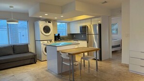 A modern kitchen with a central island, built-in appliances, and a dining area. - Bright Coastal 2BR Apartment #10 (Pompano Beach)
