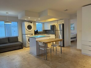 Una cocina moderna con una isla central, electrodomésticos integrados y un comedor.