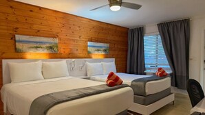 A hotel room with two beds, a ceiling fan, and artwork on the walls. - Bright Coastal 2BR Apartment #10 (Pompano Beach)