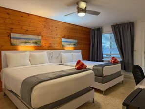 Una habitación de hotel con dos camas, un ventilador de techo y obras de arte en las paredes.