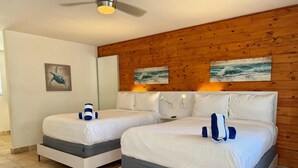 Un dormitorio con dos camas, paneles de madera en la pared y obras de arte.