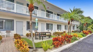 Un hotel de dos pisos con mobiliario exterior y palmeras.