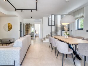 A modern interior with a dining area, sofas, a staircase, and a view to the outside. - Vacation home Dream by Interhome (Krk/Dobrinj)