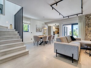 A modern interior with a staircase, a dining area, a sofa, and a kitchen. - Vacation home Dream by Interhome (Krk/Dobrinj)