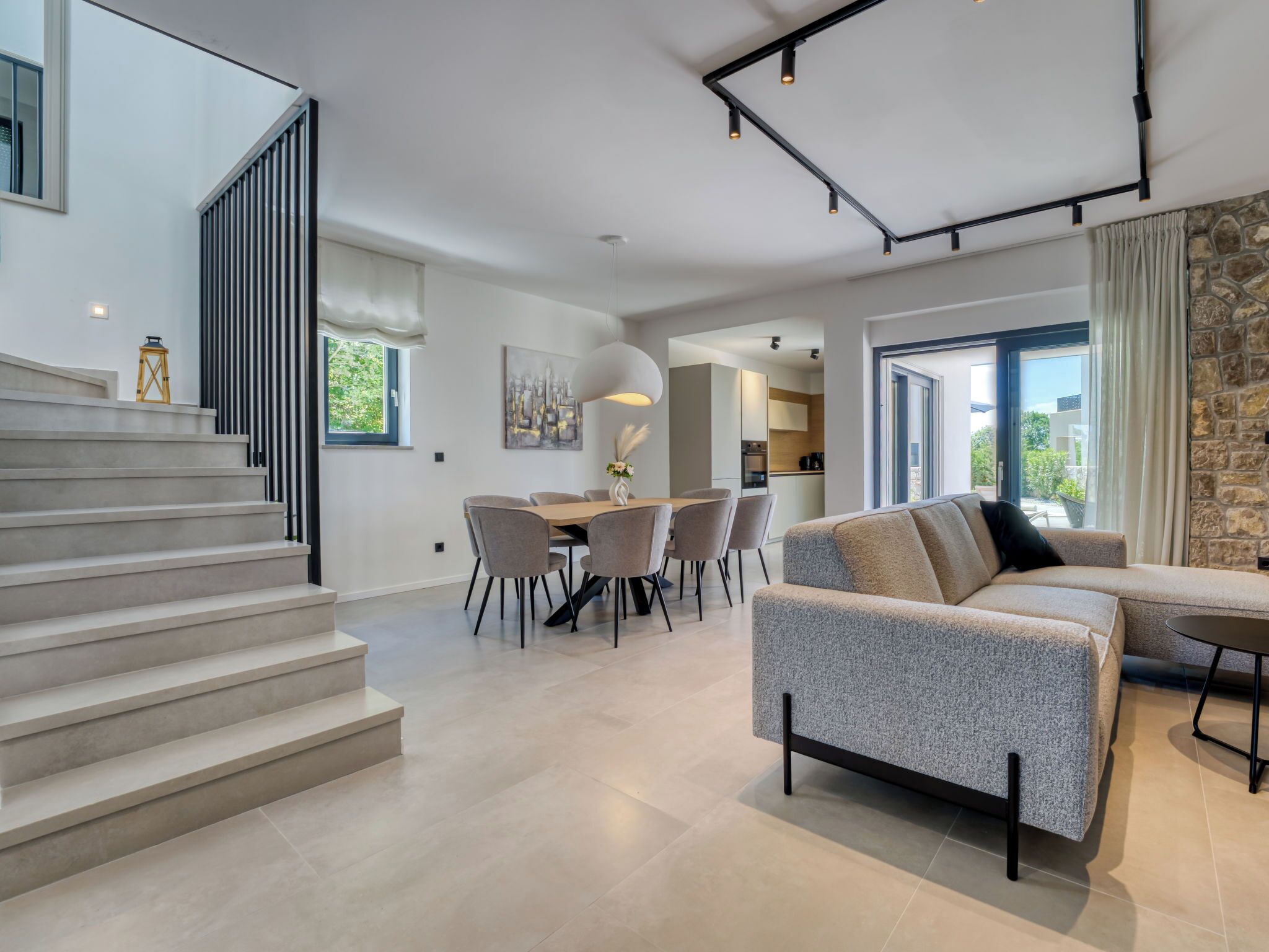 A modern interior with a staircase, a dining area, and a living room with a sofa.