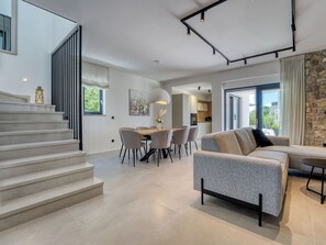 Een modern interieur met een trap, een eethoek en een woonkamer met een bank.