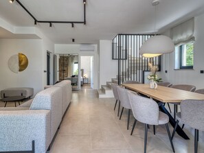 Een modern interieur met een eethoek, banken, een trap en uitzicht op de omgeving.
