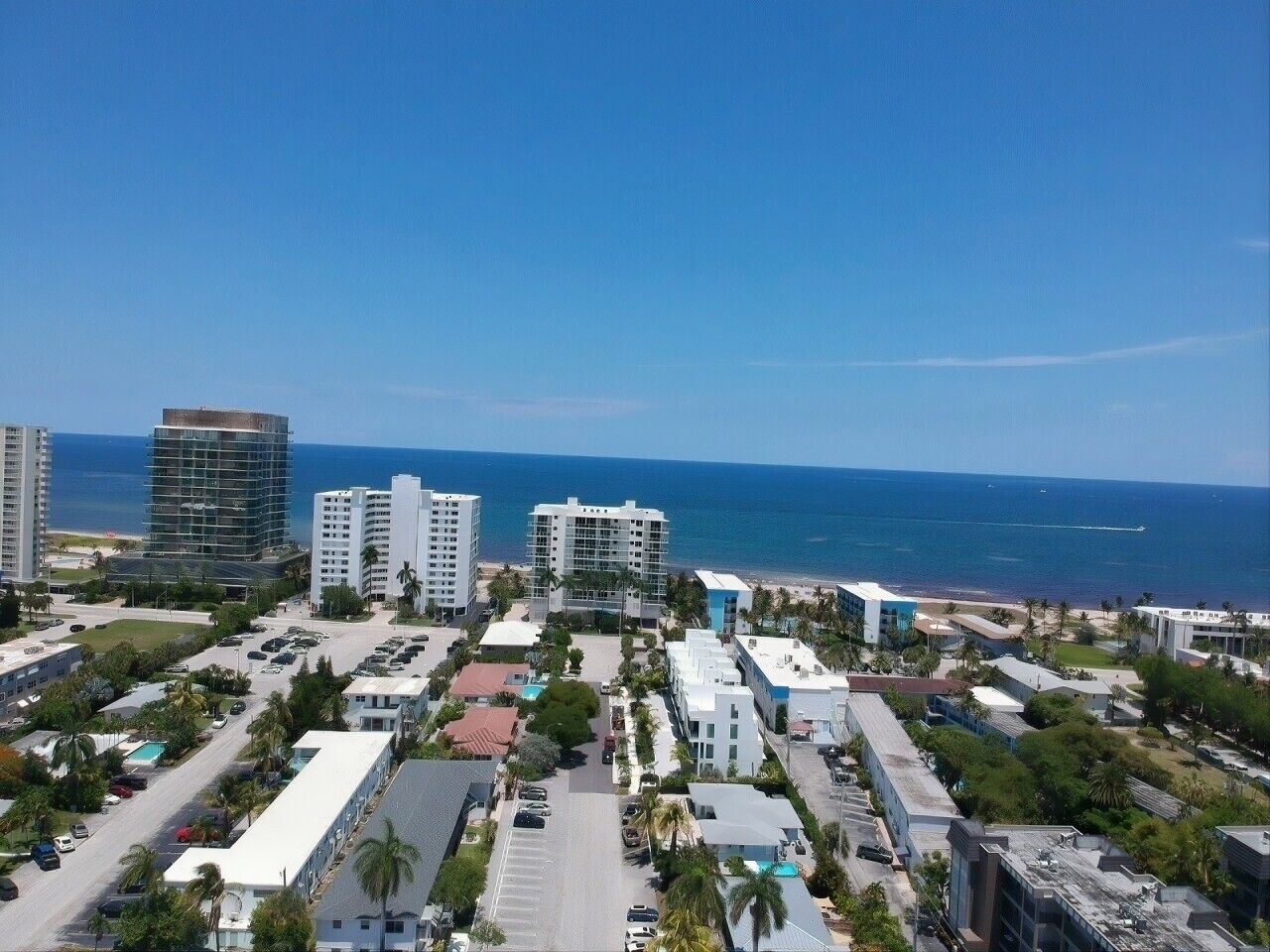 A coastal urban area with high-rise buildings, a parking lot, and a view of the ocean.