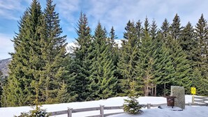 Schneebedeckte Landschaft mit Holzpfeilung, immergrünen Bäumen und einer Steinstruktur.