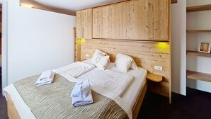 Ein Schlafzimmer mit einem Holzkopfende, einem Bett mit weißer Bettwäsche, einem Nachttisch und einem Regal mit einem Bilderrahmen.
