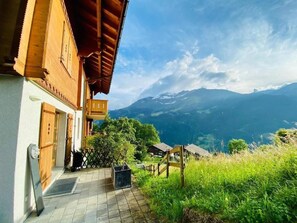 Ein Hotel mit Bergblick, mit Holzfassade, überdachtem Außenbereich und Blick auf ferne Berge.