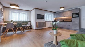 Un salon moderne comprenant un coin repas, une cuisine et un téléviseur à écran plat fixé au mur.