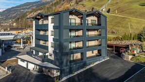 Ein mehrstöckiges Hotel mit modernem Design, mit Balkonen, einem Parkplatz und Blick auf die umliegende Landschaft.