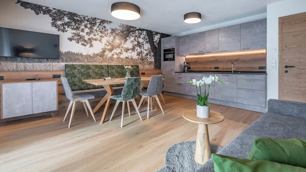 Eine moderne Küche mit grauen Schränken, einer Holz Arbeitsplatte und einem eingebauten Backofen.