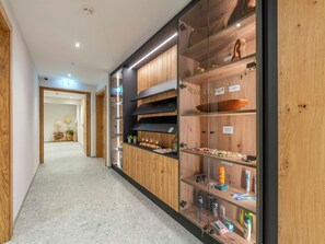 Ein Korridor mit Holzwandverkleidung, einer Vitrine mit verschiedenen Gegenständen und einer Tür zu einem anderen Raum.