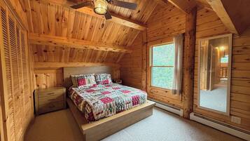 A wooden cabin bedroom with a bed, nightstands, a ceiling fan, and a window.