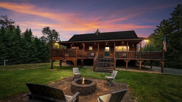 A wooden cabin with a deck, a fire pit, and two chairs. - 7SD Cozy Log Cabin near Bretton Woods with Hot Tub, Firepit, Private Year (Twin Mountain)