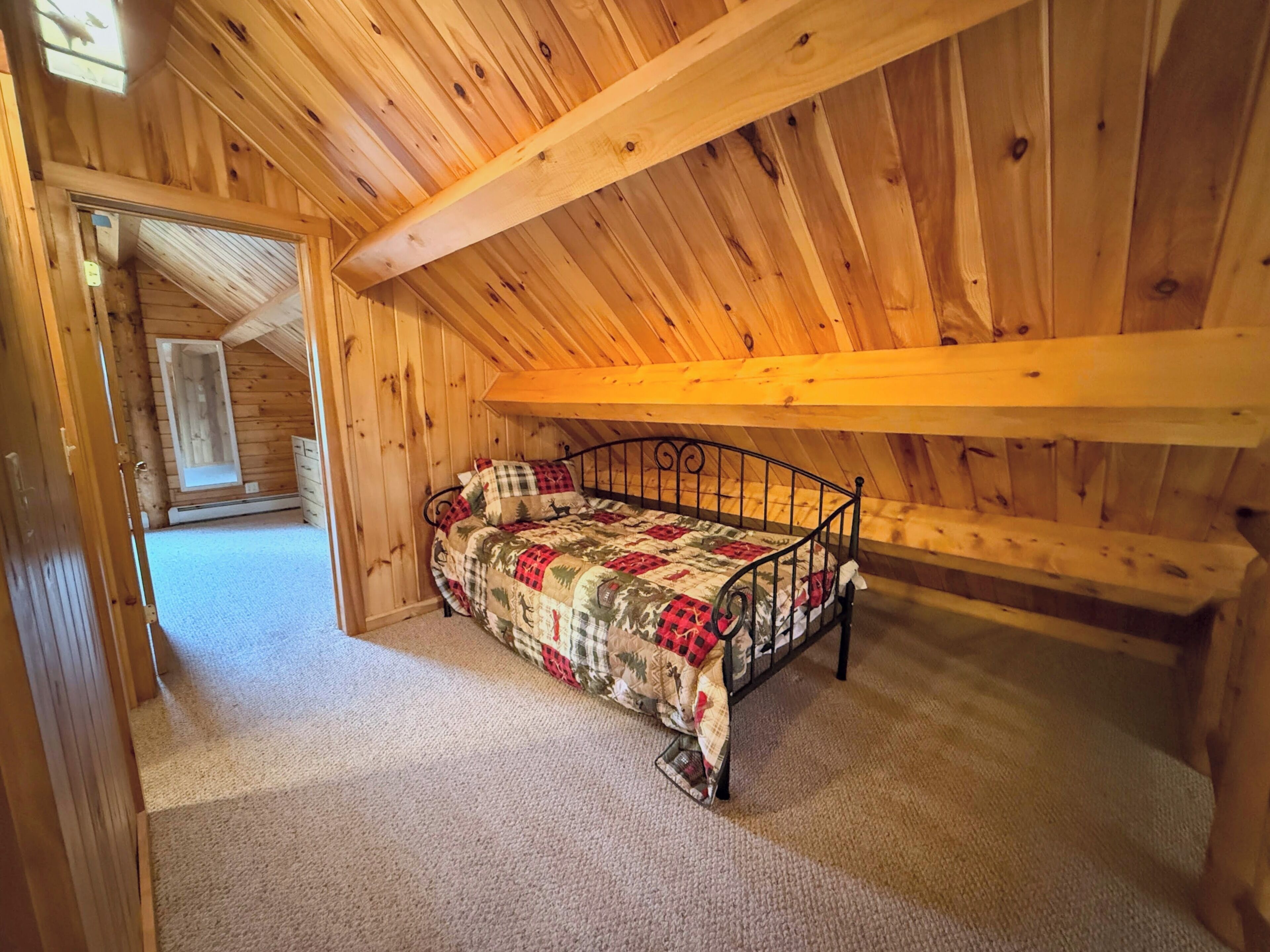Una habitación de madera con cama, ventana y puerta.