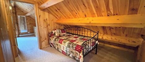 Una habitación de madera con cama, ventana y puerta.