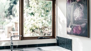 A bathroom with a window, a sink, and a framed floral artwork on the wall. - Rosey Knoll Cottage ~ Cottage with delights of modern life (Daylesford)