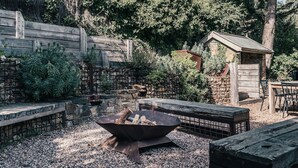 A rustic outdoor area with a fire pit, wooden benches, and a stone wall. - Rosey Knoll Cottage ~ Cottage with delights of modern life (Daylesford)