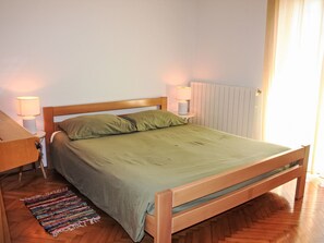 A neatly made bed with a wooden headboard, two bedside lamps, and a colorful rug on a wooden floor. - Große Wohnung in Pješčana Uvala mit Eigenem Balk by Interhome (Pula/Banjole)