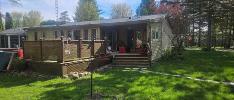 A single-story house with a front porch, a fenced yard, and a satellite dish.