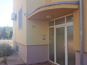 A building with a number '26' on the wall, a door with a glass panel, and a small outdoor area with plants. - Zentrale Ferienwohnung mit überdachtem Balkon by Interhome (Crno)