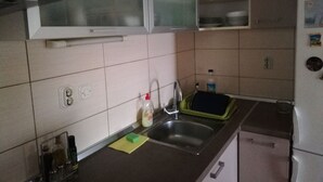 Keittiössä on pesuallas, astiankuivausteline ja kaappeja.