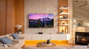 Un salon moderne doté d’un téléviseur à écran plat, d’une cheminée, d’un canapé et d’étagères décoratives.