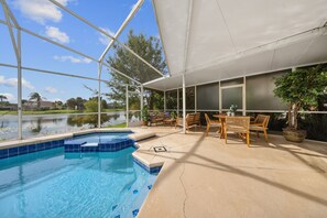 A pool area with a clear view of a lake, outdoor furniture, and a covered patio. - 2900 LC - Oak Island Harbor Retreat (Kissimmee)