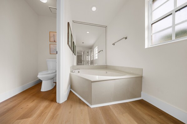 Une salle de bain moderne équipée de toilettes, d’une baignoire et d’un espace douche.