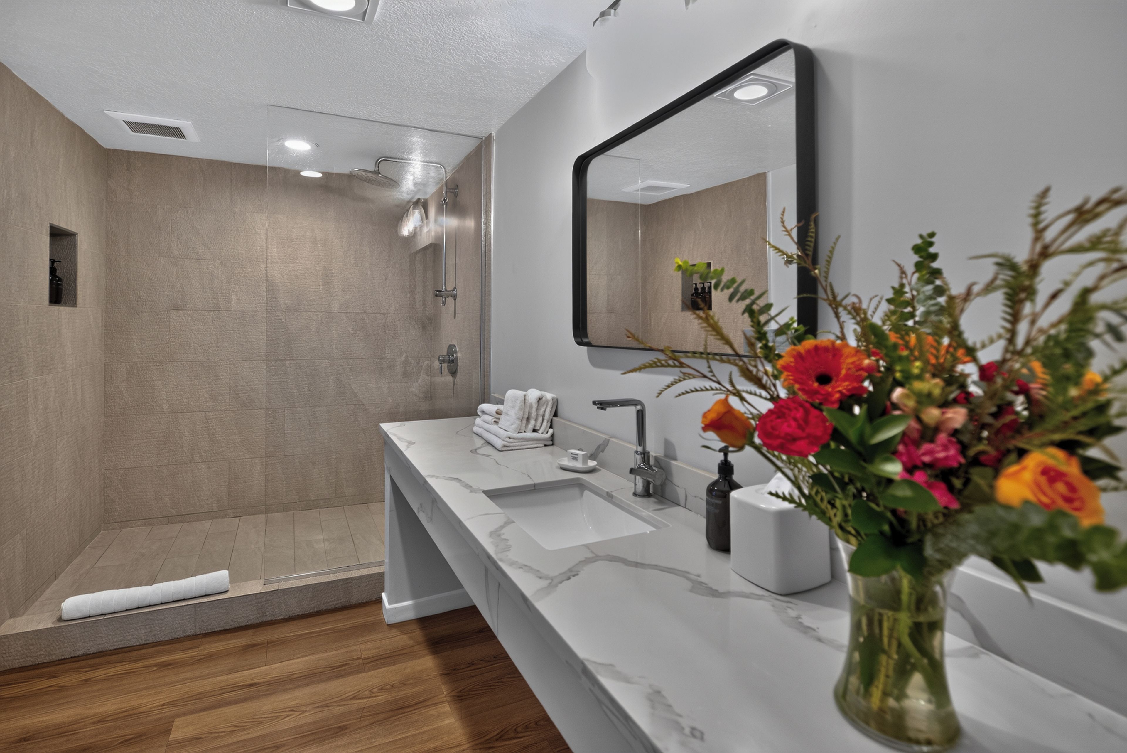 A modern bathroom with a shower, a sink, and a mirror.