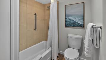 Un baño moderno con bañera, inodoro y cortina de ducha.