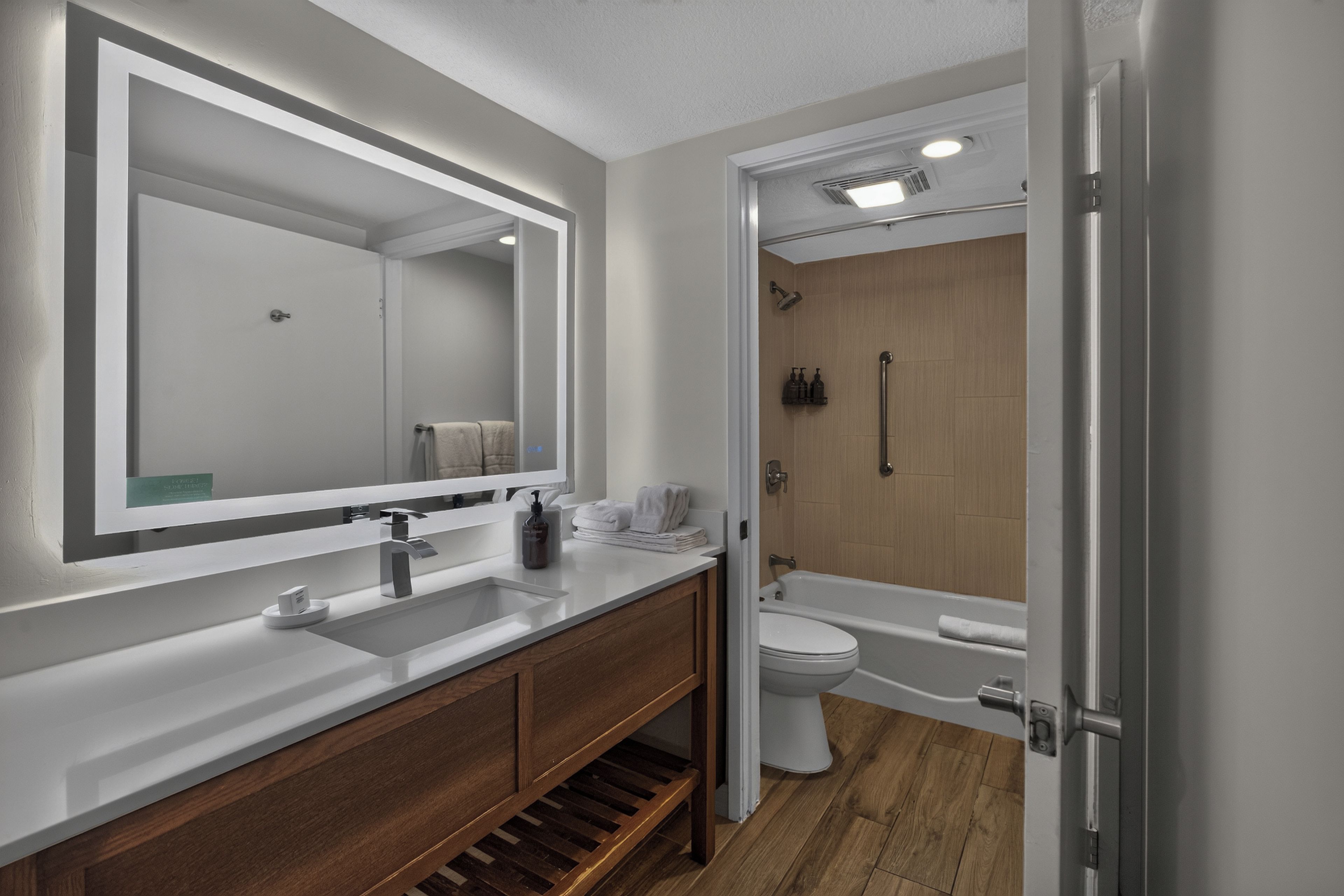 Ein modernes Badezimmer mit großem Spiegel, Waschbecken, Toilette und Duschbereich.