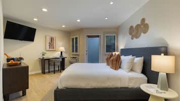 Habitación de hotel con una cama grande, un escritorio, un televisor de pantalla plana y una puerta que da a otra habitación.