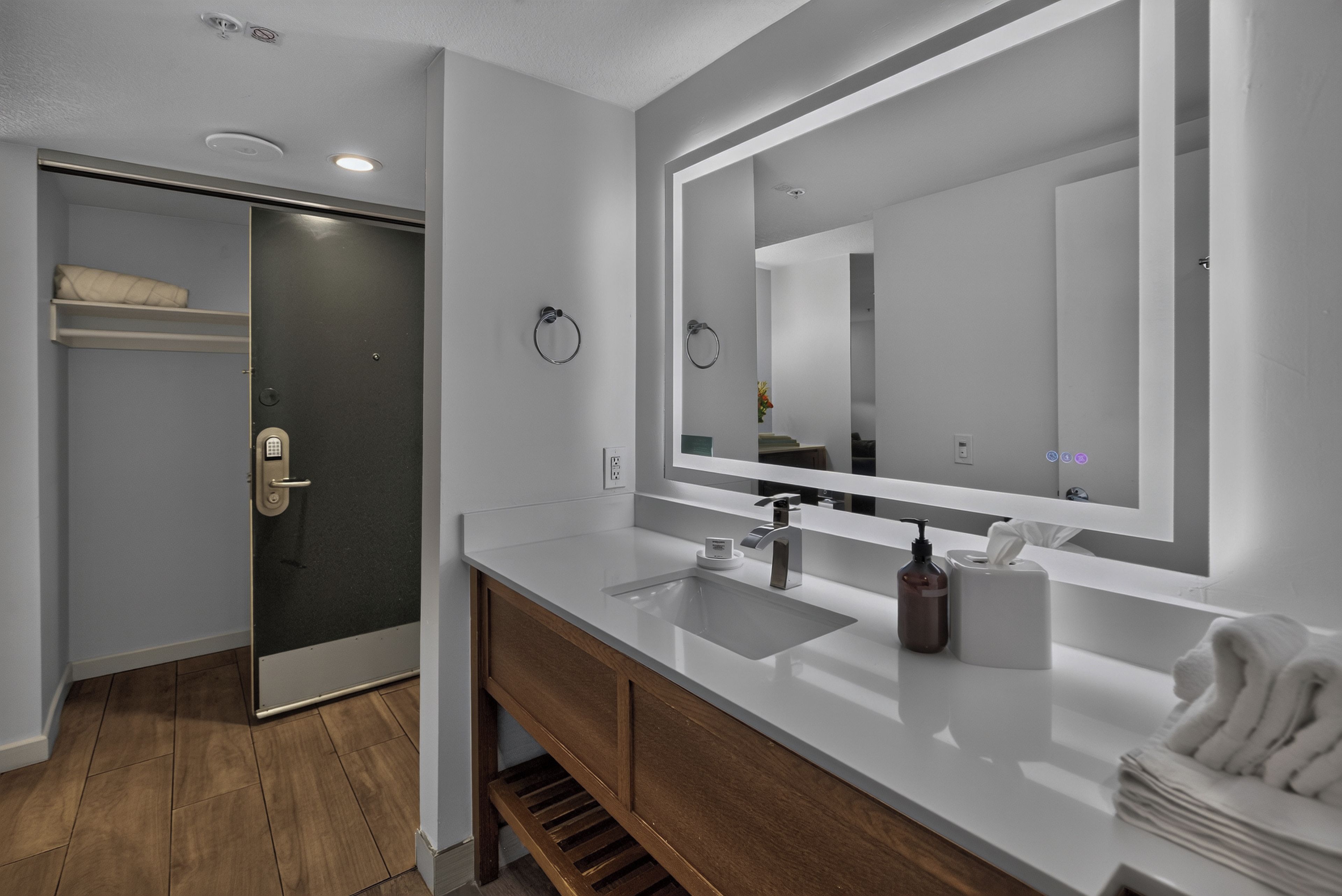 Une salle de bain moderne avec un grand miroir, un lavabo et un porte-serviettes.