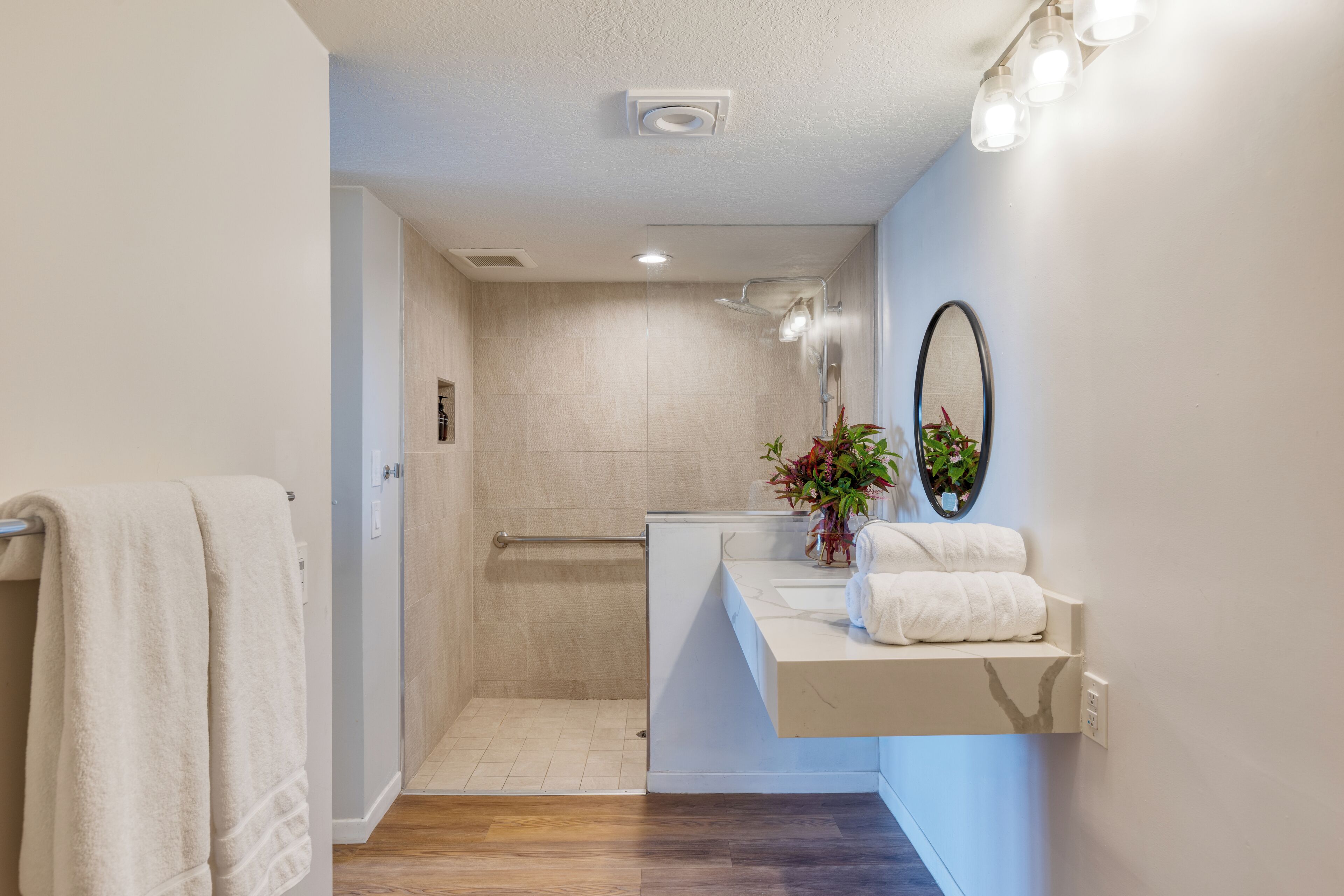 A modern bathroom with a shower, a vanity with a mirror, and a towel rack.