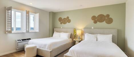 A hotel room with two beds, a window with shutters, a wall-mounted air conditioner, and a decorative wall piece.