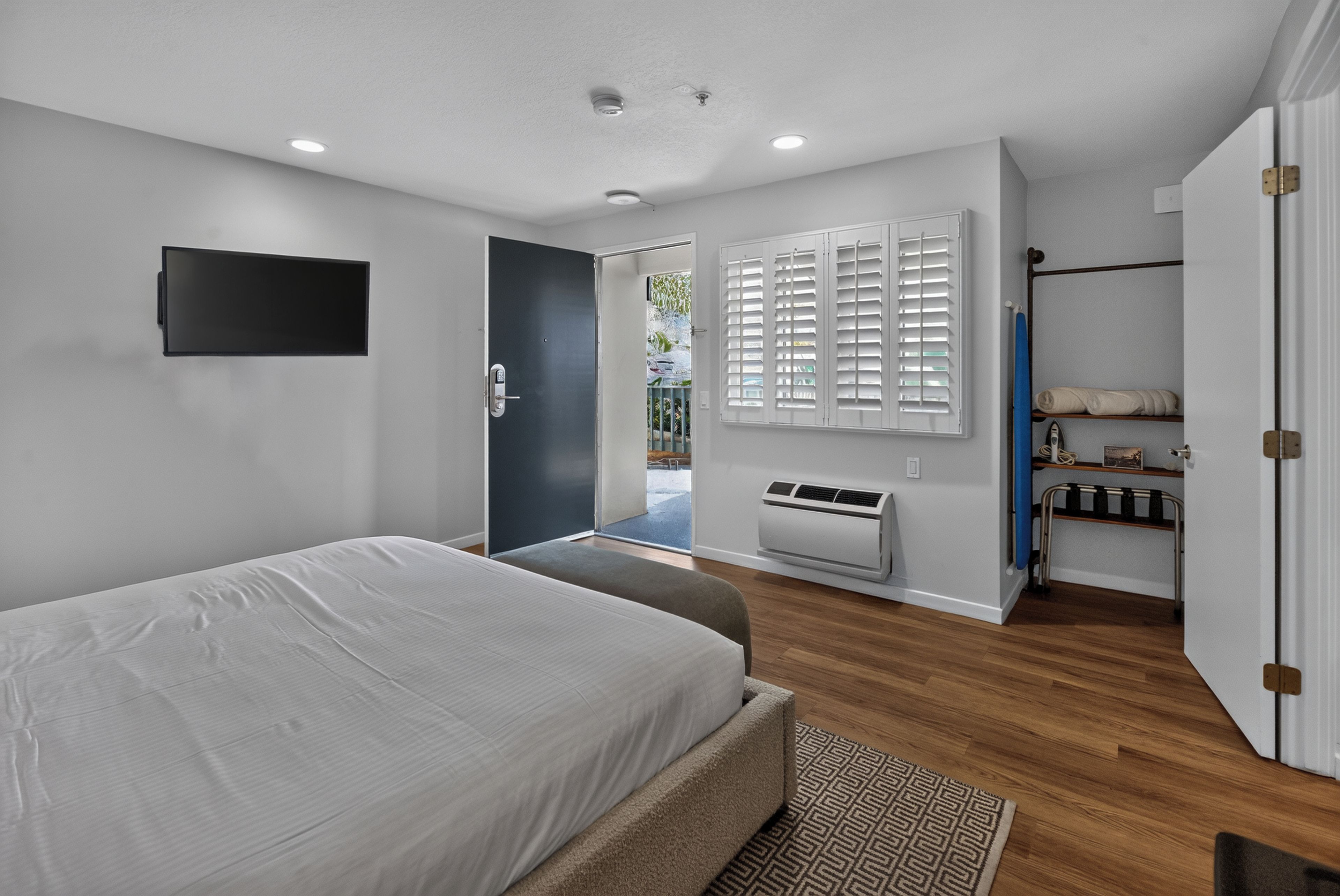 Quarto moderno com cama, televisão, guarda-roupa e ar condicionado instalado.