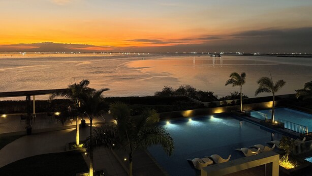 A pool area with a view of the sea and a sunset. - Bayshore Residential Resort 2 Phase 1 (Parañaque)