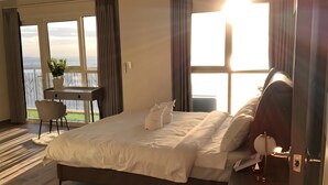 A hotel room with a bed, a desk, a chair, and a view of the sea. - Bayshore Residential Resort 2 Phase 1 (Parañaque)