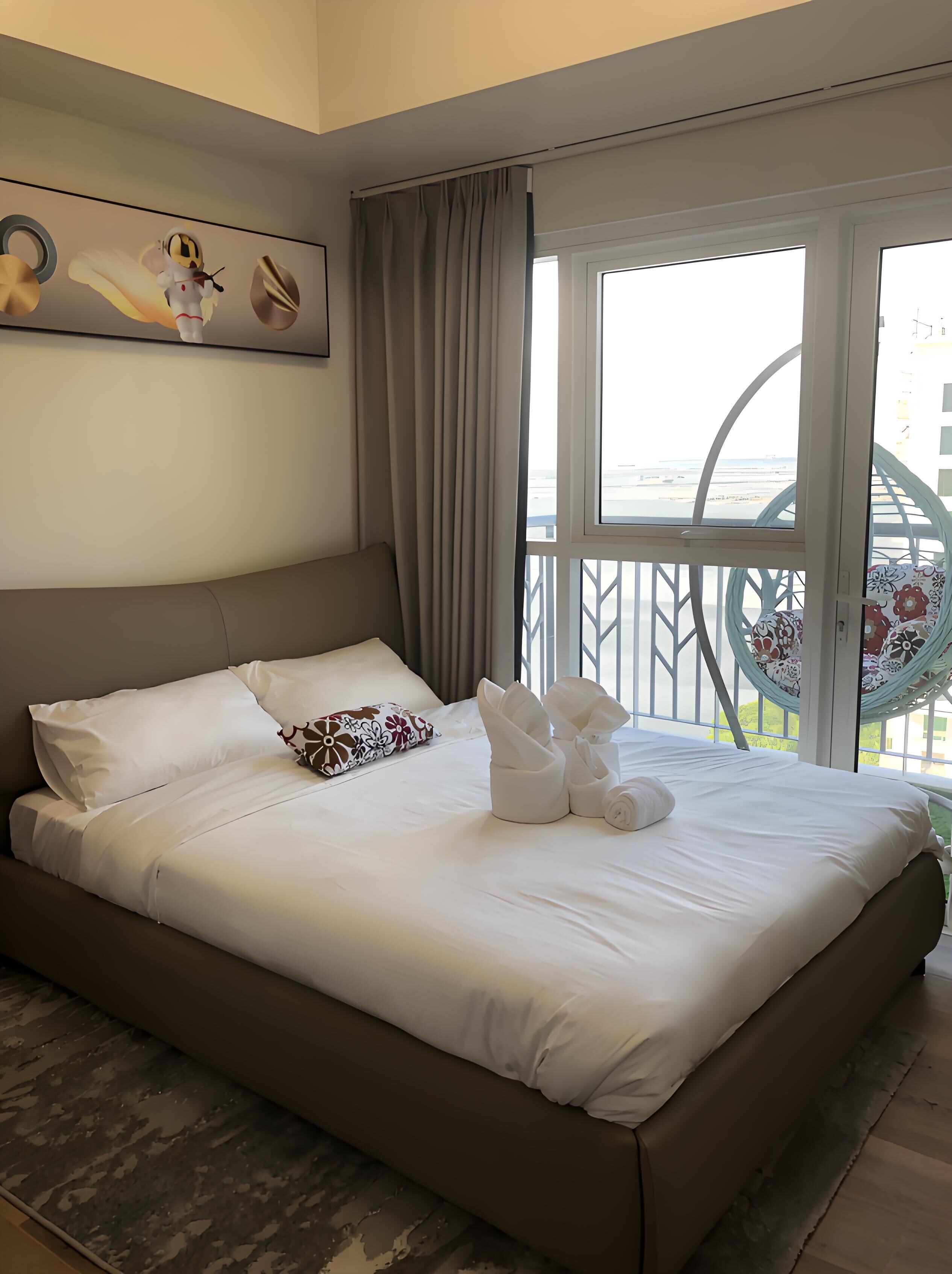 A hotel room with a large bed, a view of the beach, and a hammock chair.
