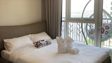 A hotel room with a large bed, a view of the beach, and a hammock chair.