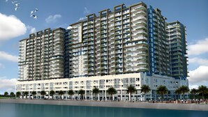 A multi-story residential building with balconies, a swimming pool, and palm trees. - Bayshore Residential Resort 2 Phase 1 (Parañaque)