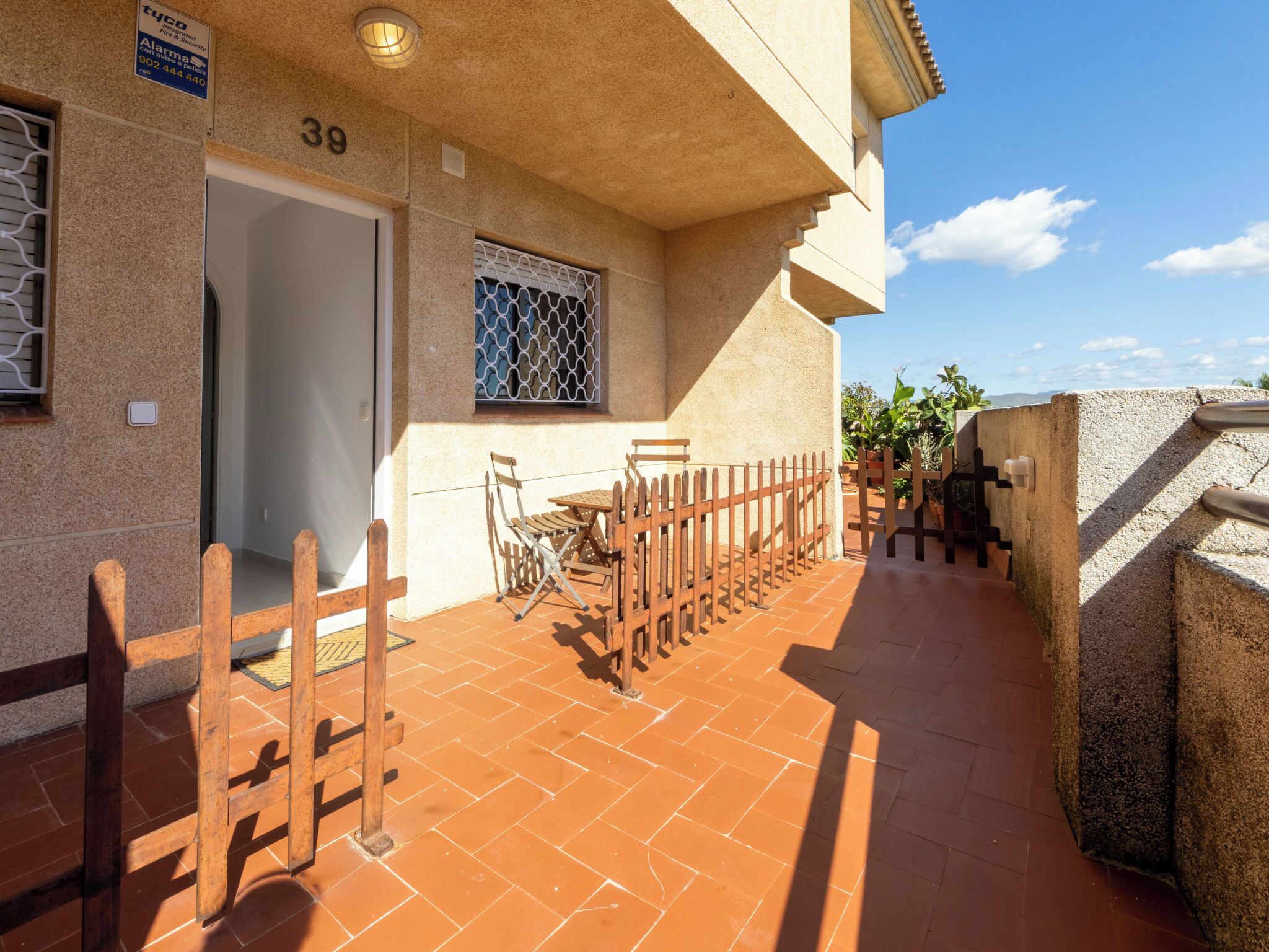 A building with a tiled patio, a wooden fence, and a door marked with the number 39.
