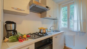 Een moderne keuken met een gasfornuis, een koffiezetapparaat en verse groenten op het aanrecht.