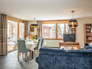 Ein modernes Wohnzimmer mit Essbereich, Fernseher und Bücherregal.