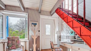 A room with a wooden staircase, a chair with a floral cushion, a wooden coat rack, and a desk with books. - La Chapelle by Interhome (Tréguier)